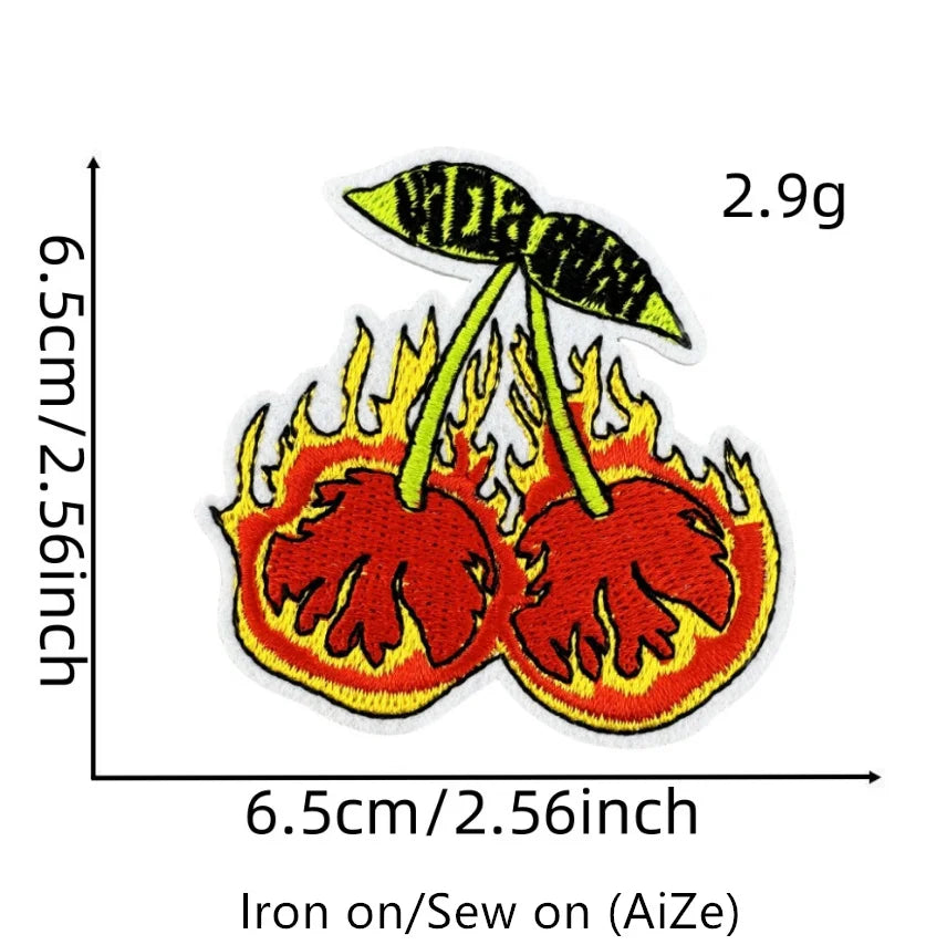 A yellow and orange embroidered patch depicting a stylized cherry engulfed in flames, designed for iron-on application.