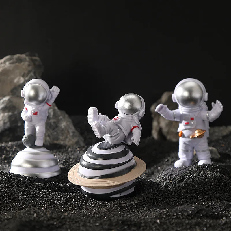 Three handcrafted astronaut figurines in white and silver on a dark surface.