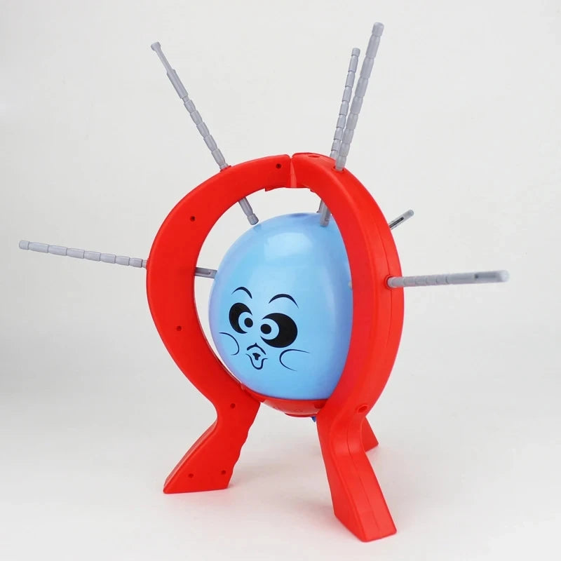 A red game piece featuring a blue balloon and several thin sticks, used for a family strategy game.