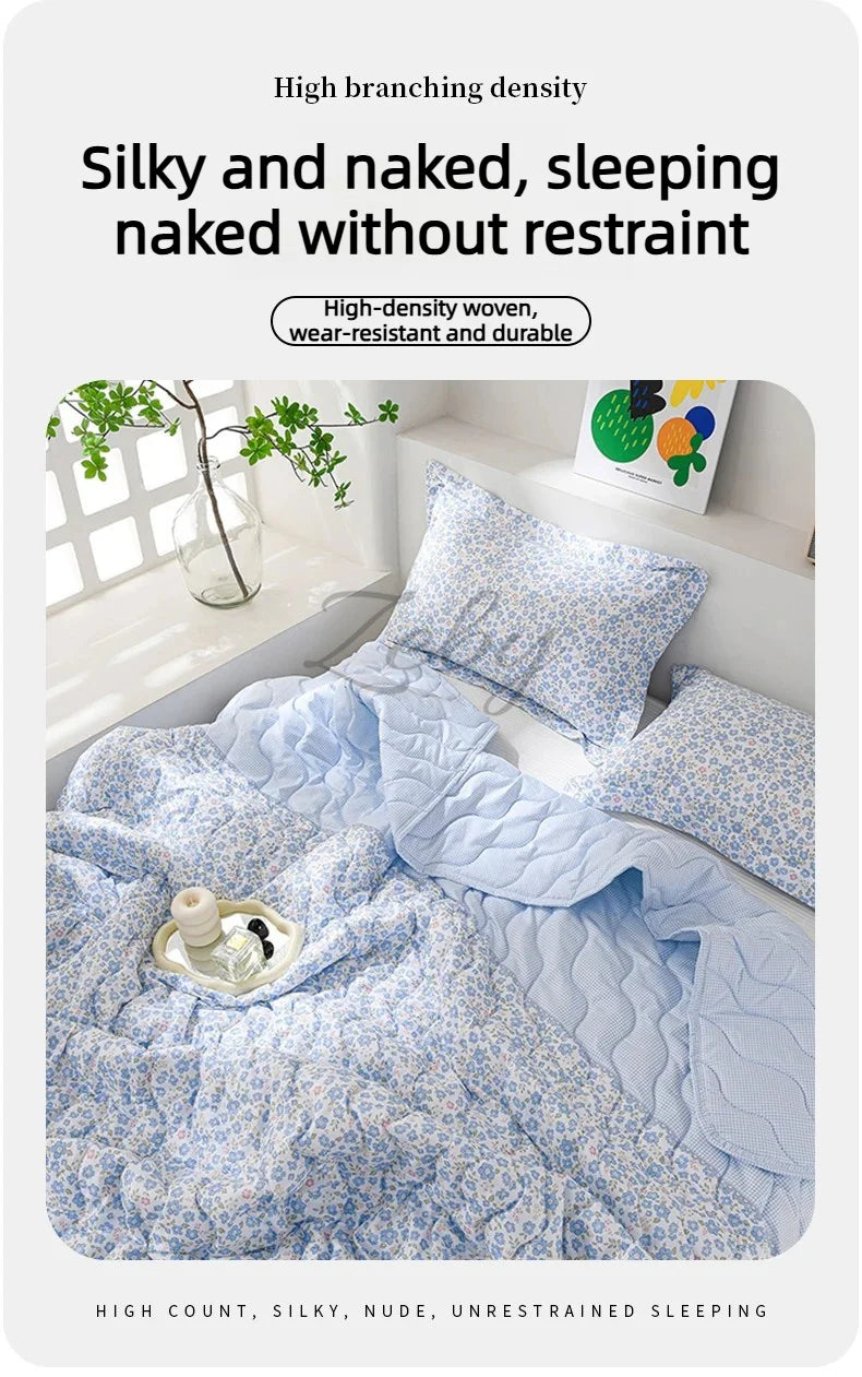 A light blue quilted blanket with a floral pattern is shown folded on a bed, emphasizing silky and naked, unrestrained sleepi