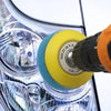 A close-up view of a car headlight restoration kit with sanding discs and polishing pads being used on a lens.