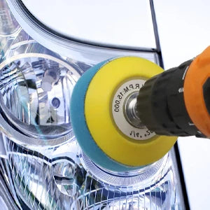 A close-up view of a car headlight restoration kit with sanding discs and polishing pads being used on a lens.