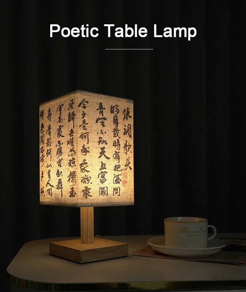 A poetic table lamp with a rectangular linen shade and wooden base, illuminated to display calligraphy.