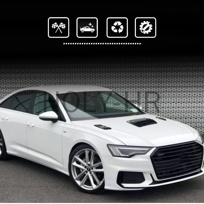 A white sedan with an aftermarket hood scoop cover installed, shown in a studio setting.
