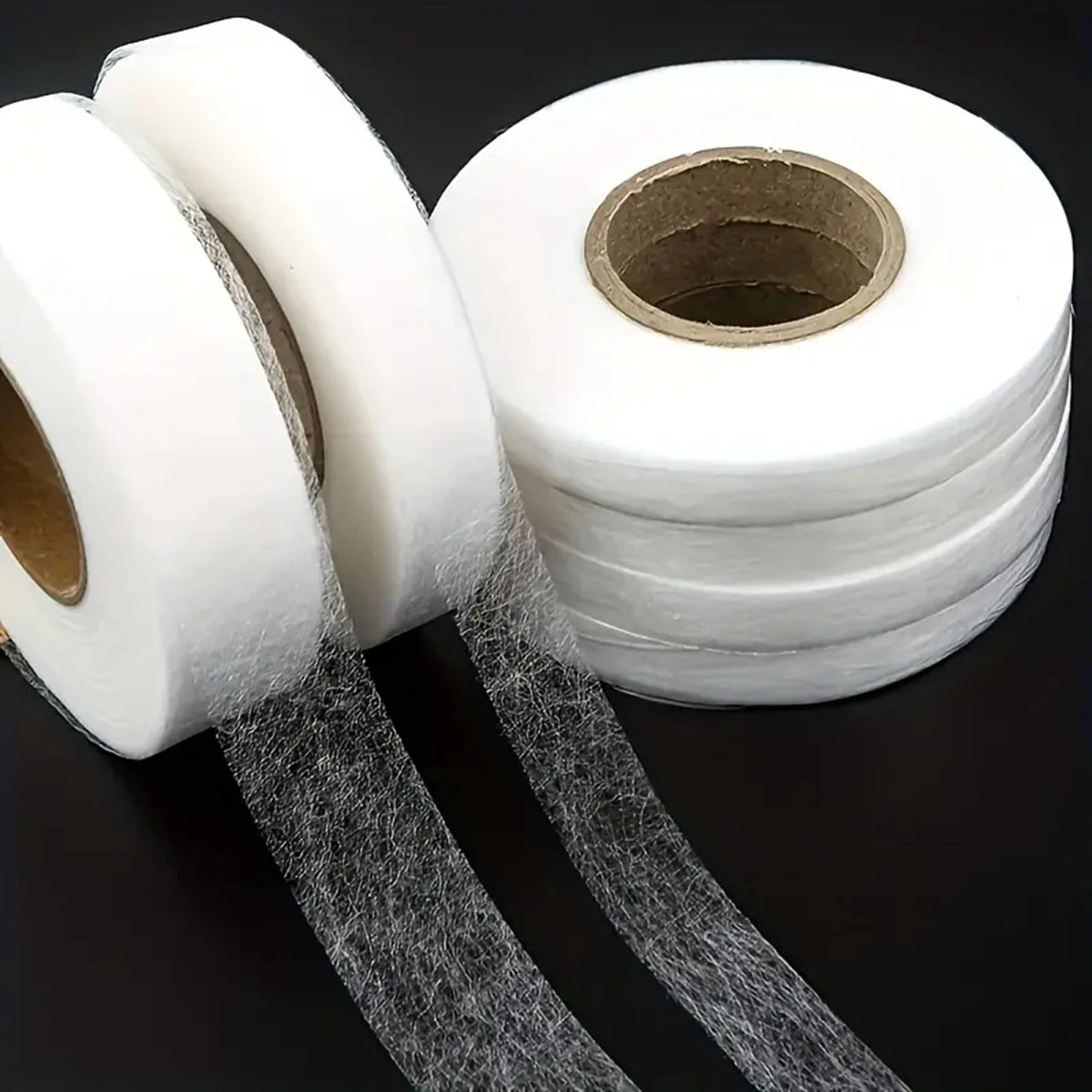 Rolls of white no-sew iron-on hem tape for instant clothing repairs with strips unwound.