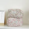 A pink floral quilted makeup bag with a zipper closure resting on a white surface.