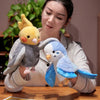 A woman holds an adorable plush parrot hand puppet toy for kids with gray and yellow feathers.