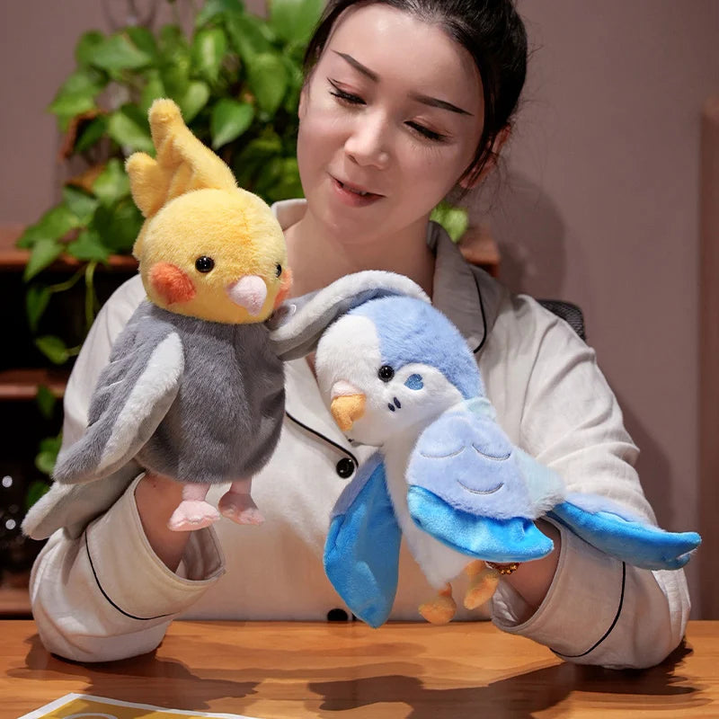 A woman holds an adorable plush parrot hand puppet toy for kids with gray and yellow feathers.