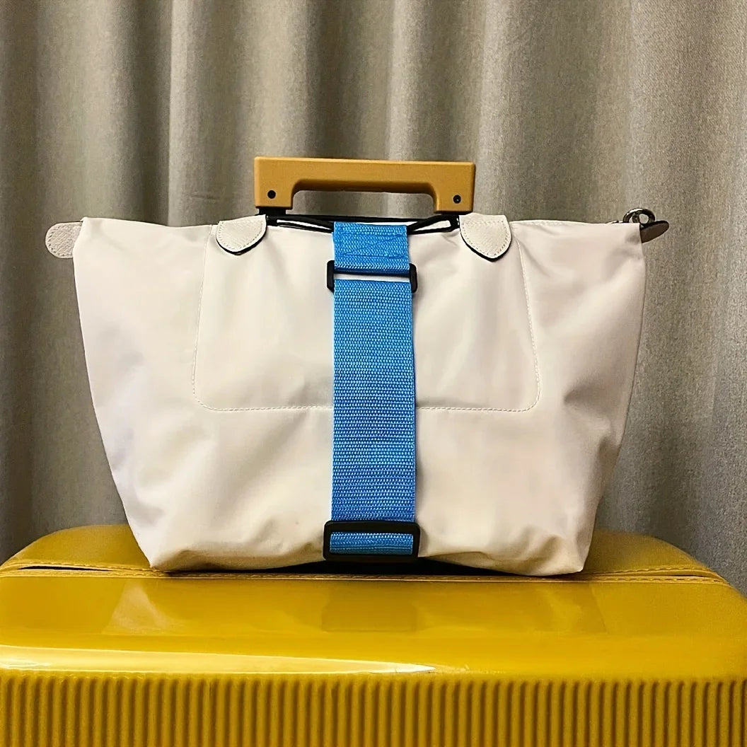A white reusable elastic luggage strap with a blue adjustable strap is displayed on a yellow surface.