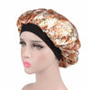 A woman wearing a satin hair bonnet with an ornate floral pattern and a black elastic band.