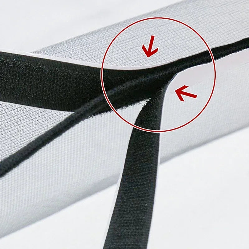 Close-up view of a black self-adhesive mosquito window screen being folded or attached to a white fabric surface.