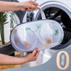 A hand is placing a mesh laundry bag for delicates into a washing machine drum.