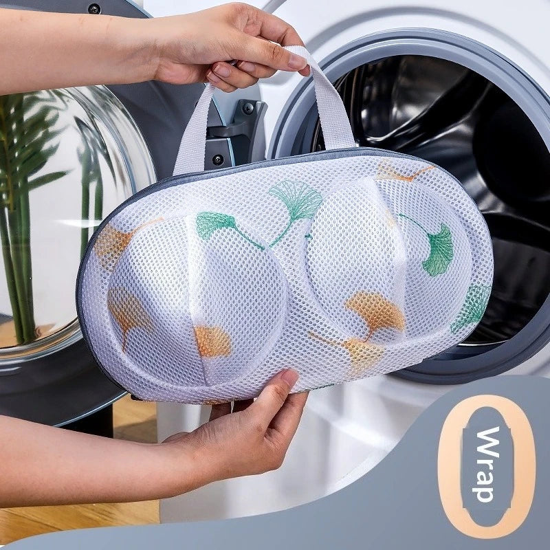 A hand is placing a mesh laundry bag for delicates into a washing machine drum.