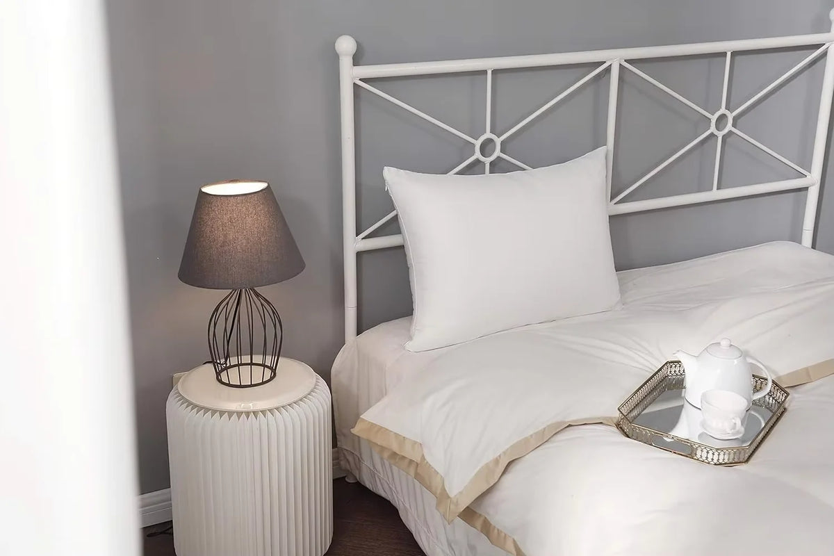 Un ensemble de literie blanche avec un plateau argenté sur une tête de lit en bois blanc.