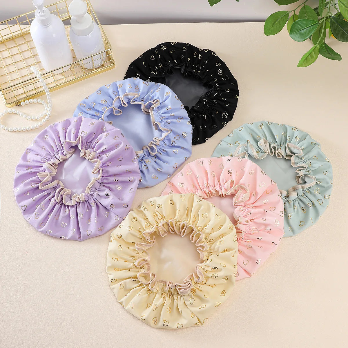 A collection of reusable elastic shower caps in purple, blue, pink, and cream colors are displayed on a light surface.