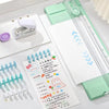 A close-up of an A4 mini paper trimmer with precision cutter in mint green and silver, showing the trimming blades and paper.