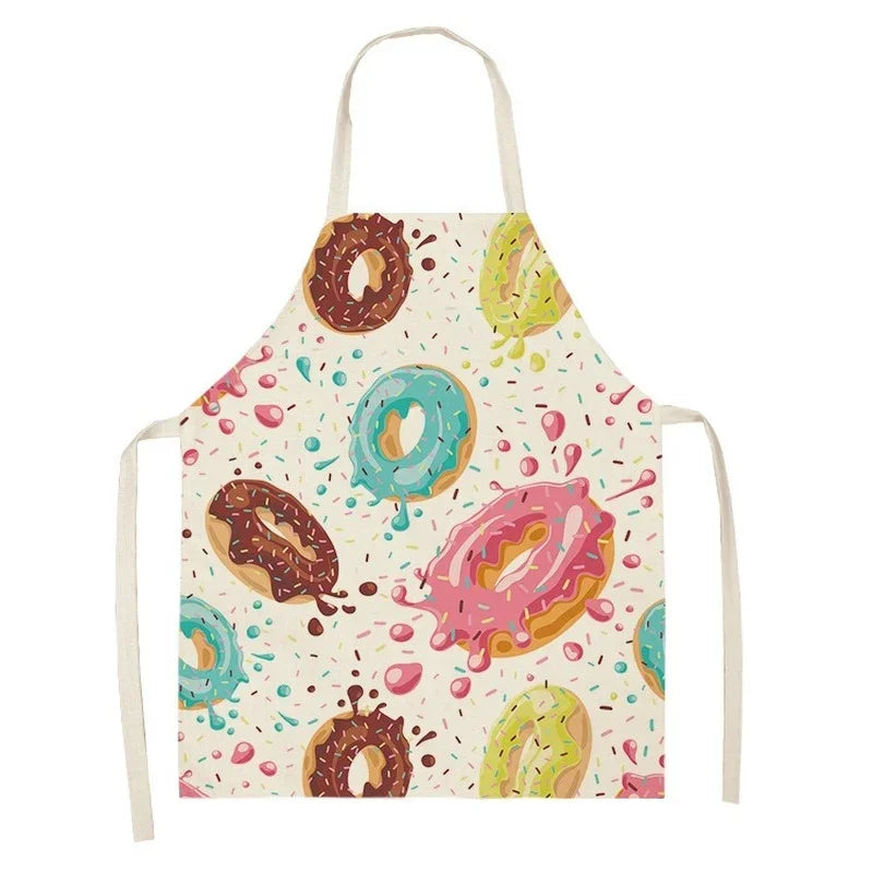 A colorful linen kitchen apron featuring various donut designs on a light background.