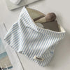 A white and blue striped makeup bag with a zipper, featuring a makeup brush and a leather product inside.