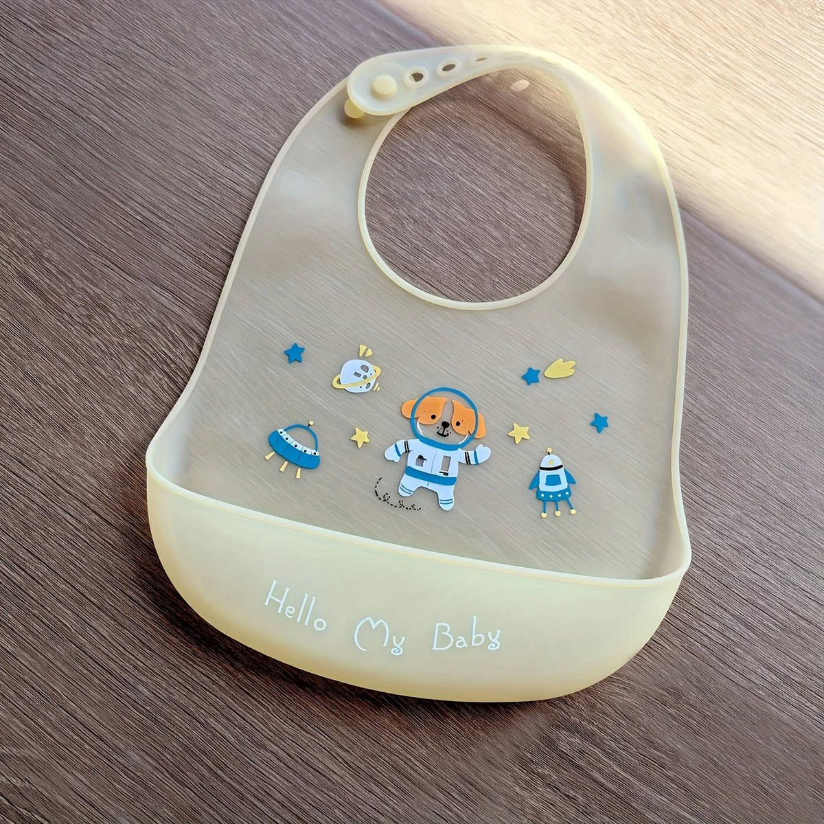A light beige silicone baby bib featuring a cute cartoon animal print and the text Hello My Baby.