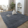 A fluffy gray rug with white accent pillows placed in a bright living room setting.