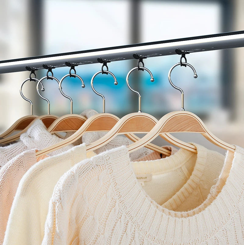 A display of cream and beige knitted sweaters hanging from a metal rack with silicone hooks.
