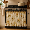 A black stove with a floral oven skirt featuring yellow and green flowers and a ruffled trim.