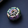 A close-up shot of a precision metal fidget spinner with iridescent purple and green colors resting on a dark surface.