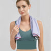 A woman models a purple microfiber sports towel top and light blue jeans against a gray background.
