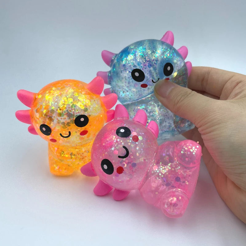 A hand holds a translucent squishy stress ball shaped like an axolotl in various colors including blue, orange, and pink.
