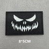 Black embroidered patch featuring a white demonic face design with hook and loop backing