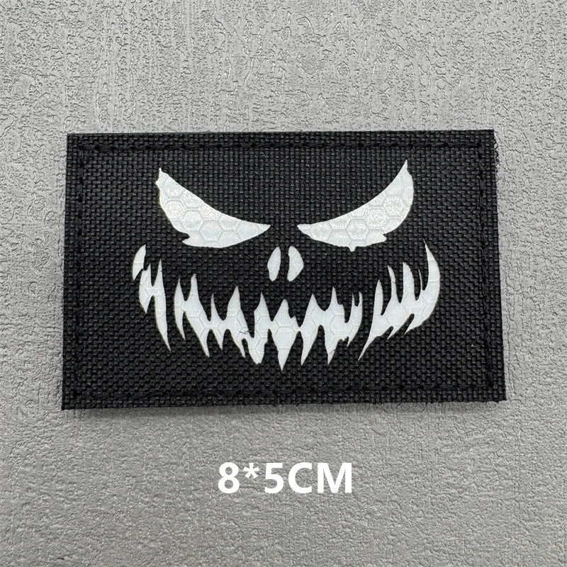 Black embroidered patch featuring a white demonic face design with hook and loop backing