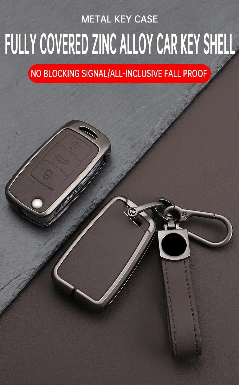 A dark metal key case cover for a car key, shown with a leather strap and a metal keyring.