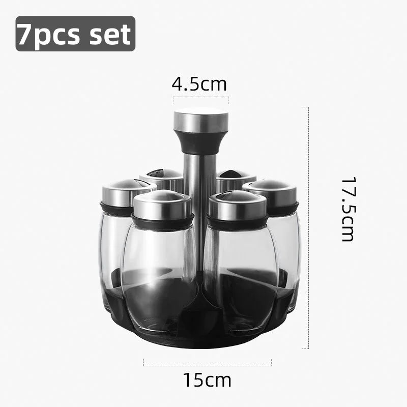 A set of seven clear glass spice jars with black lids and a rotating rack, shown in a top-down view.