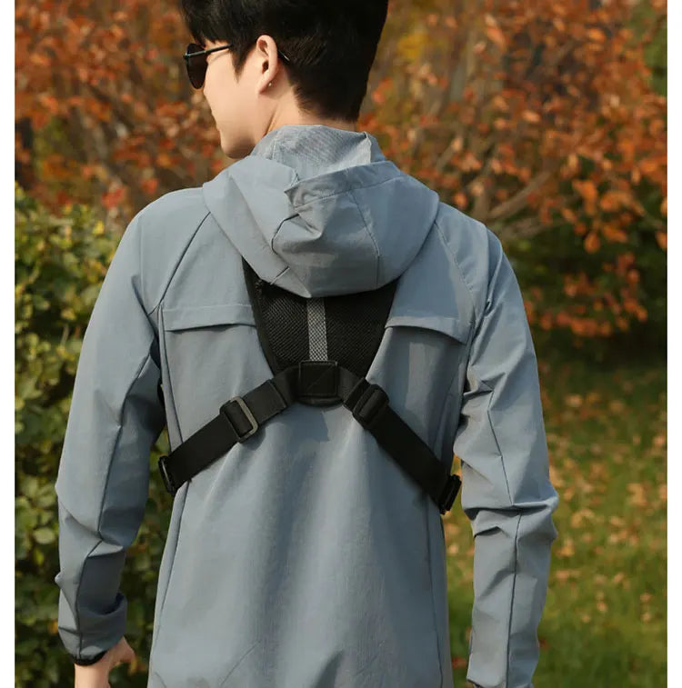 Person trägt einen hellblauen taktischen Brustgurt mit Laufvest über einer Jacke, von hinten gesehen.