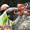 A worker wearing a helmet and high-visibility vest is using a power tool to cut material.