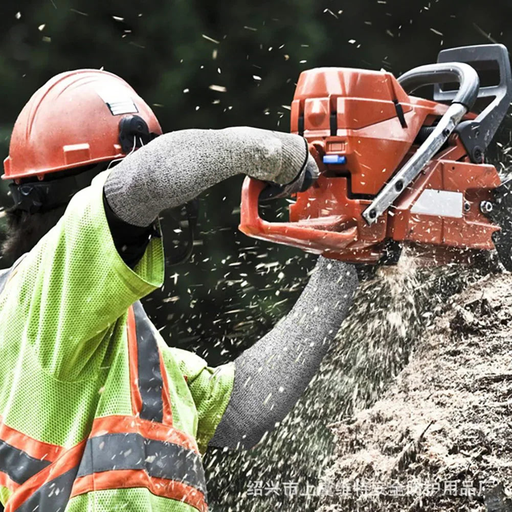 A worker wearing a helmet and high-visibility vest is using a power tool to cut material.