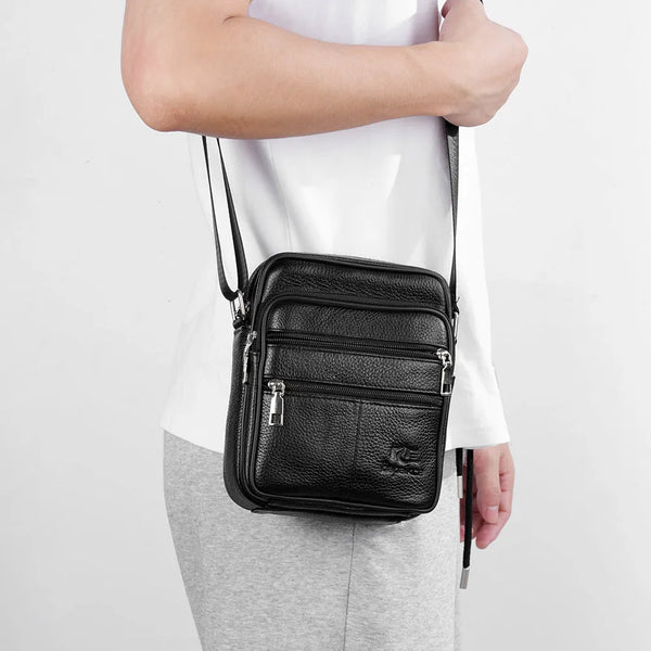 Black vintage leather messenger bag with silver hardware carried by a person.