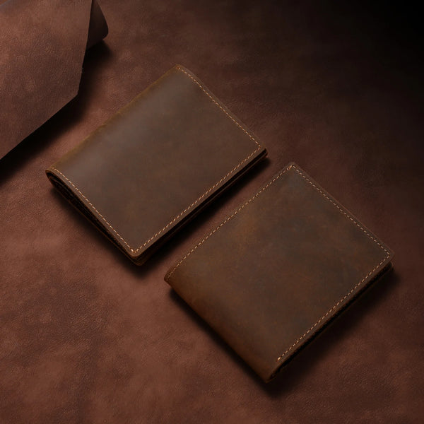 A pair of brown vintage crazy horse leather slim RFID-blocking bifold wallets resting on a dark brown surface.