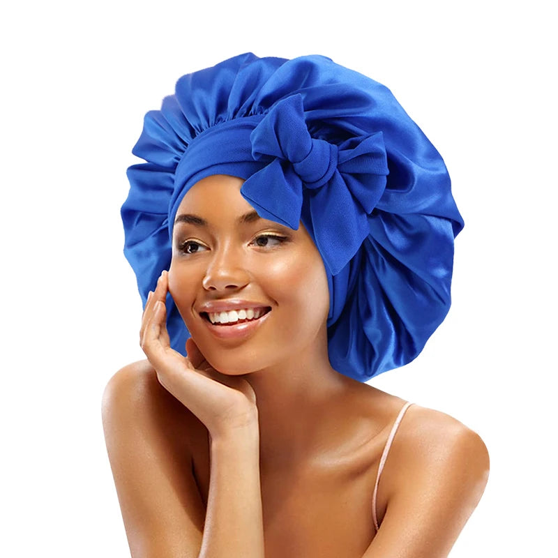 A woman wearing a royal blue satin sleeping bonnet with an adjustable tie.