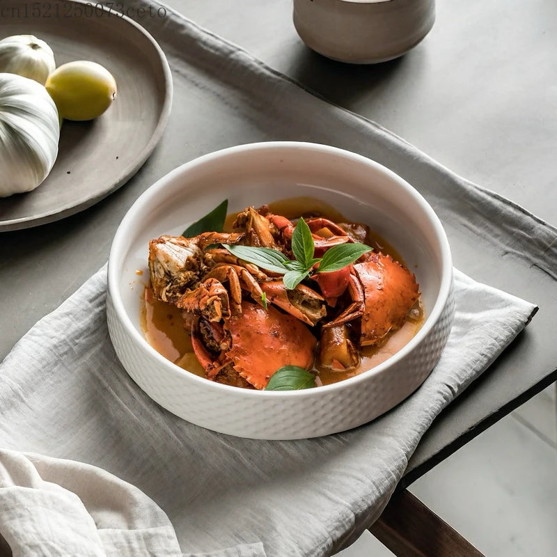 A white ceramic soup bowl filled with a savory orange-colored broth and pieces of cooked meat, resting on a gray linen cloth.