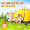 A family is relaxing inside a bright yellow, weather-proof tent outdoors on green grass.