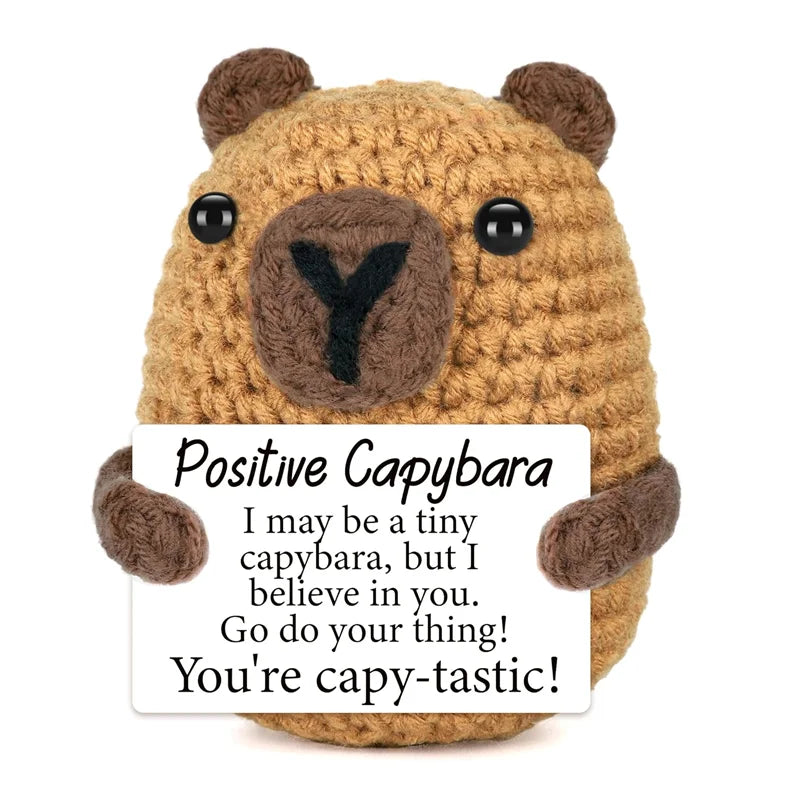 A handmade crochet capybara animal doll with a positive message card.