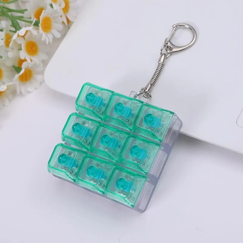 A clear green tactile clicking keyboard keychain fidget toy with a silver keyring attached.