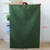 A dark olive green heavy-duty canvas laundry bag hanging vertically against a white cabinet.