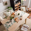 A light green and white gingham table runner is displayed on a wooden dining table with natural decor.