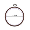 A circular wooden embroidery hoop with a metal loop for cross-stitch and needlework.