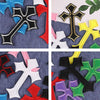 A collection of ten vibrant embroidered cross patches in various colors including black, red, yellow, green, and purple on de