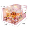 A pink wooden dollhouse miniature building kit featuring furniture and a bedroom setup.