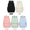 A collection of four backpacks in black, white, pink, and blue colors displayed against a white background.