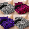 A set of three bold zebra print duvet covers in black, pink, and purple displayed on a bed.